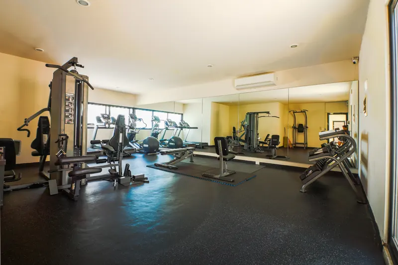 Gimnasio con caminadoras, pesas y espejos